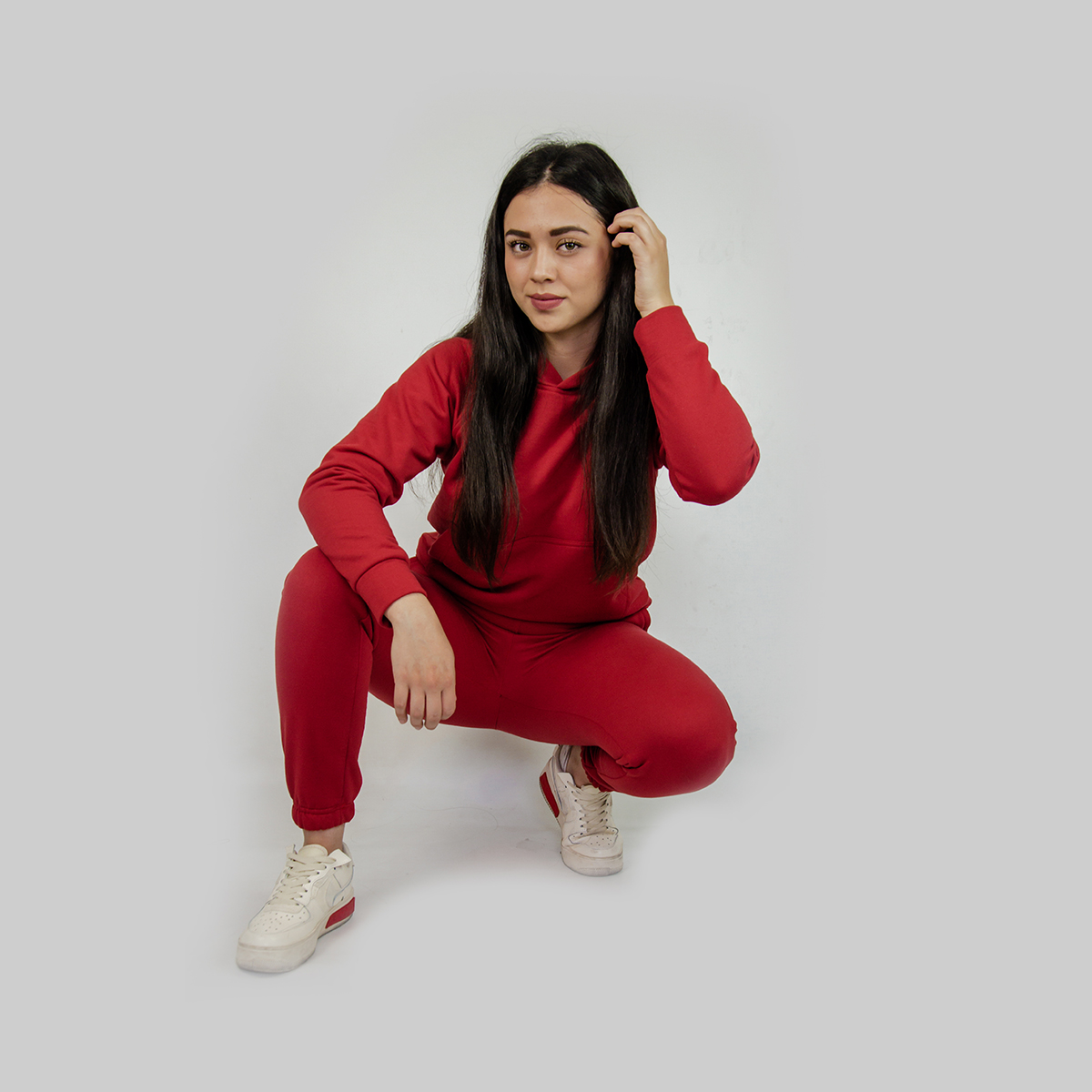 mujer arrodillada vistiendo pants y chumpa de algodon color rojo