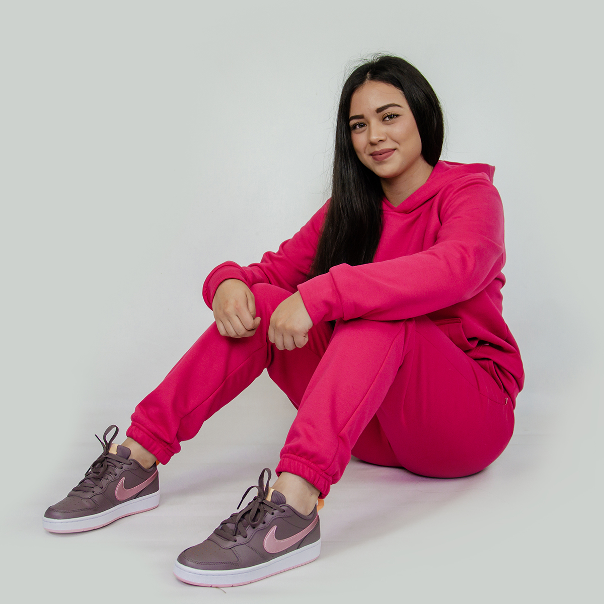 mujer sentada vistiendo pants y chumpa de algodon color rosado